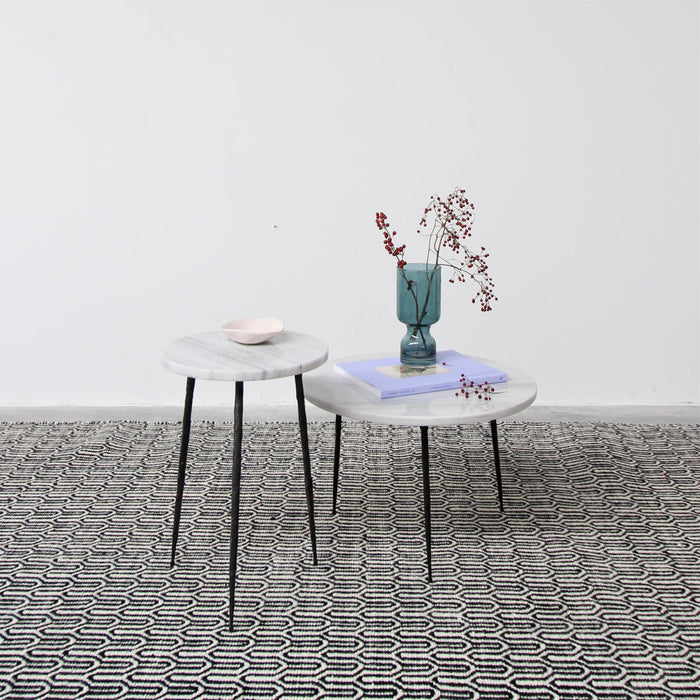 Helder tapijt in zwart/wit met wit marmeren bijzettafels van Furnified.ALT